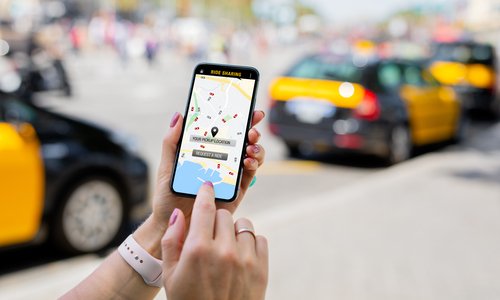 Person Using Ride Sharing App On Mobile Phone